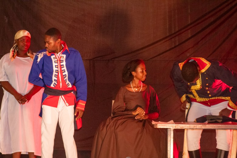 Une scène du banquet pour l’accession au trône de Dessalines, avec à gauche une émissaire en blanc et à droite l’épouse de Dessalines, Marie-Claude Heureuse Félicité Bonheur, campée par Erica Arélus.