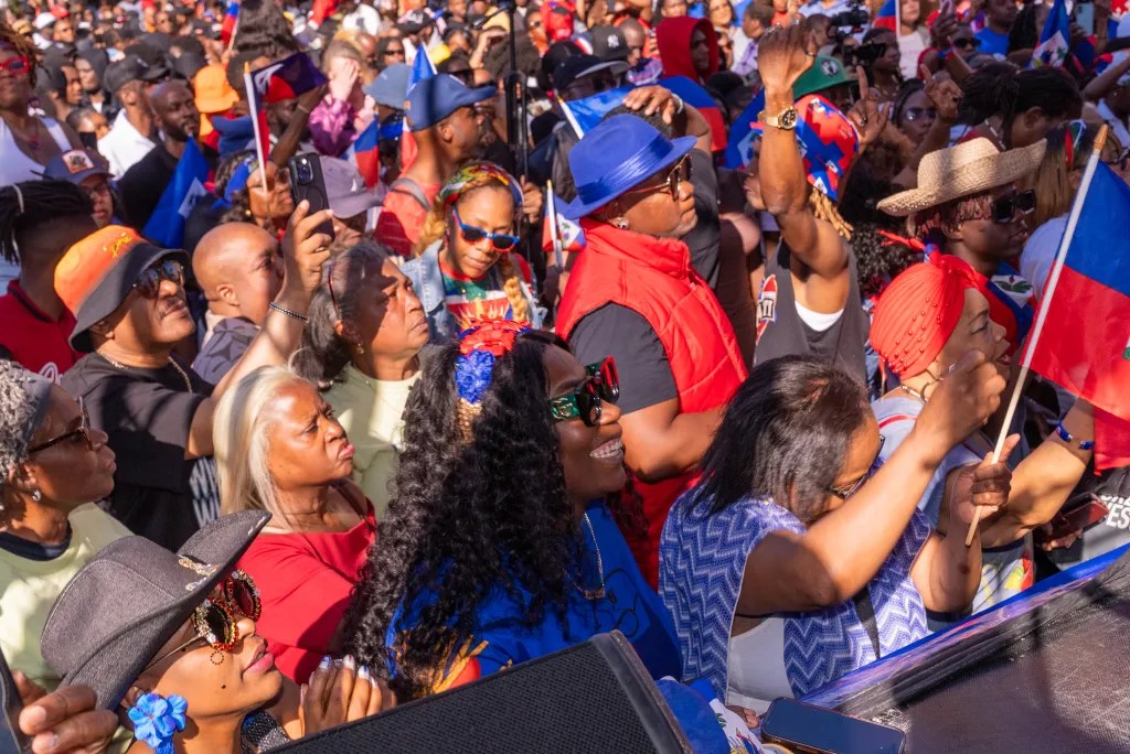 Les spectateurs apprécient la vue de devant lors de la performance live à Brooklyn de T-Vice, à l’occasion de la Journée de la Culture Haïtienne ‘L’Essence de l’Espoir’ au Hillel Place Plaza, le 10 mai 2025. Photo par Allison Hunter pour The Haitian Times.