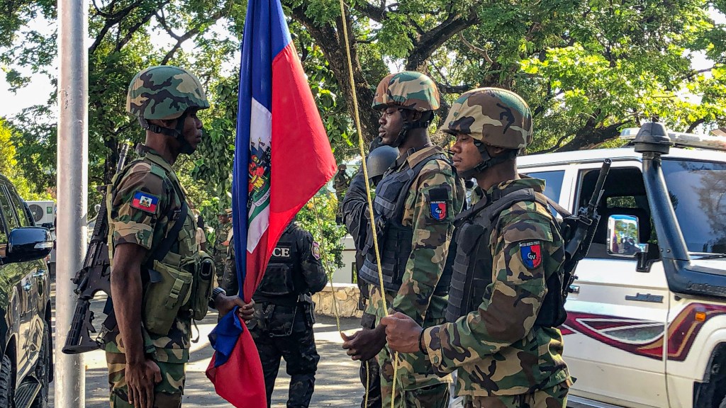 Trois officiers des Forces armées haïtiennes (FADH) se tiennent fièrement lors de la cérémonie de levée du drapeau, pour célébrer le 221ème anniversaire de l’indépendance d’Haïti. Photo par Arnold Junior Pierre pour Haitian Times.