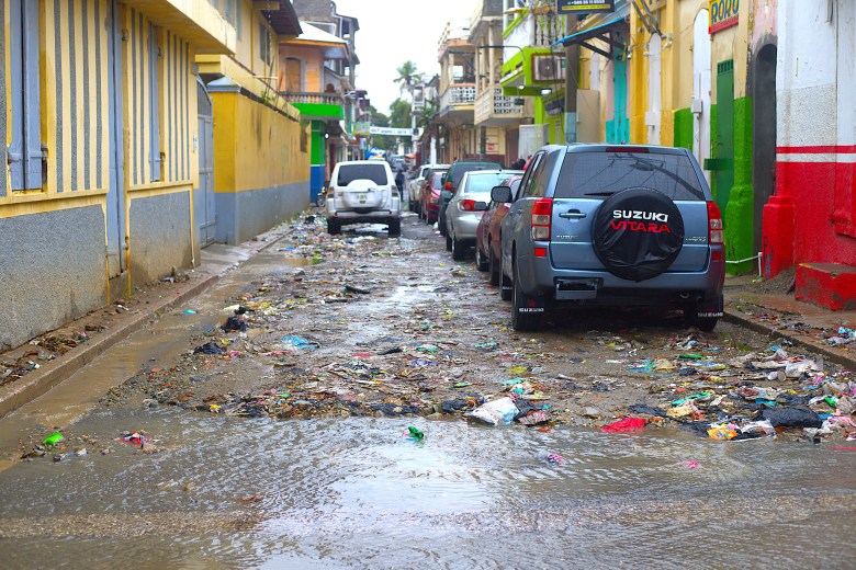 Une route boueuse et encombrée de déchets au centre-ville de Cap-Haïtien, après plusieurs heures de pluie, mardi 24 février 2026. Photo par Onz Chéry / The Haitian Times