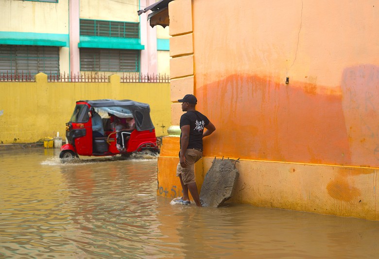 Un homme vérifiant la hauteur de l’eau dans la rue Letter A pour trouver un passage sûr mardi 24 février 2026. Photo par Onz Chéry / The Haitian Times