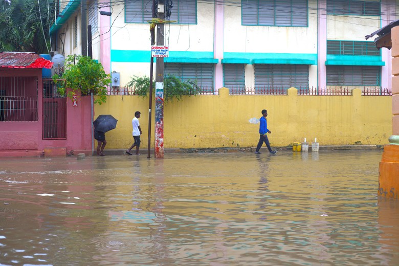 Des habitants marchent à travers l’eau de crue près du Collège Regina Assumpta, une école catholique pour filles fermée à cause des inondations, mardi 24 février 2026. Photo par Onz Chéry / The Haitian Times