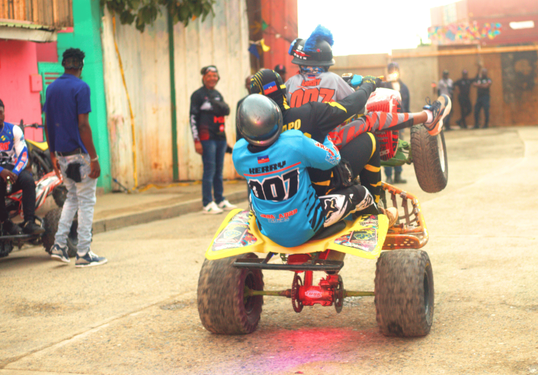 Un cascadeur effectue une wheelie avec deux passagers lors de la troisième édition de la Ruff Ryders Block Party à Cap-Haïtien le 7 mars 2026. Photo par Onz Chéry / The Haitian Times.