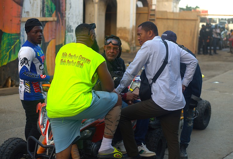 Des hommes rassemblés autour de motos lors de la troisième édition de la Ruff Ryders Block Party le 7 mars 2026, à Cap-Haïtien. Photo par Onz Chéry / The Haitian Times.