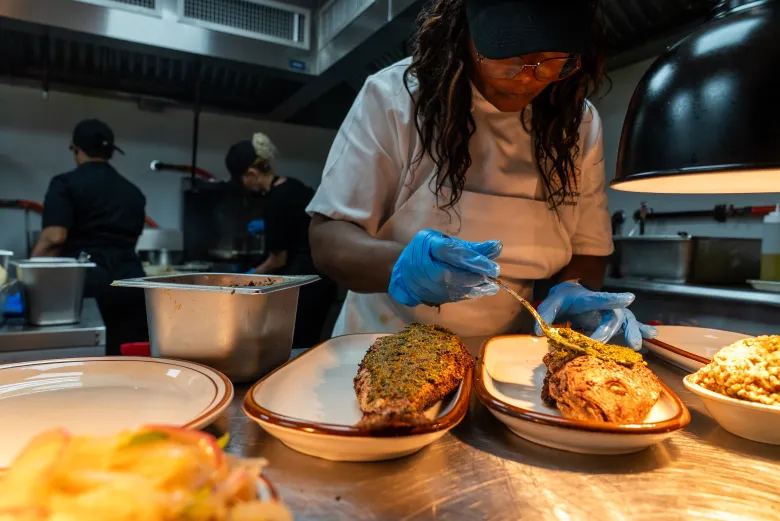 La chef Eva Volmar en cuisine dans le restaurant La Cachette du Coin à Brooklyn, vendredi 29 mai 2026. Photo d’Allison Hunter pour The Haitian Times.