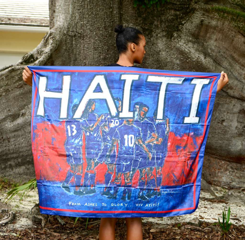 Versions of the Haiti 2026 World Cup Flag featuring the “Ashes to Glory” original painting by Bacheler Jean-Pierre and, in the last photo, Grenadier Frantzdy Pierrot with Jean Pierre. Photos courtesy of Jean-Pierre
