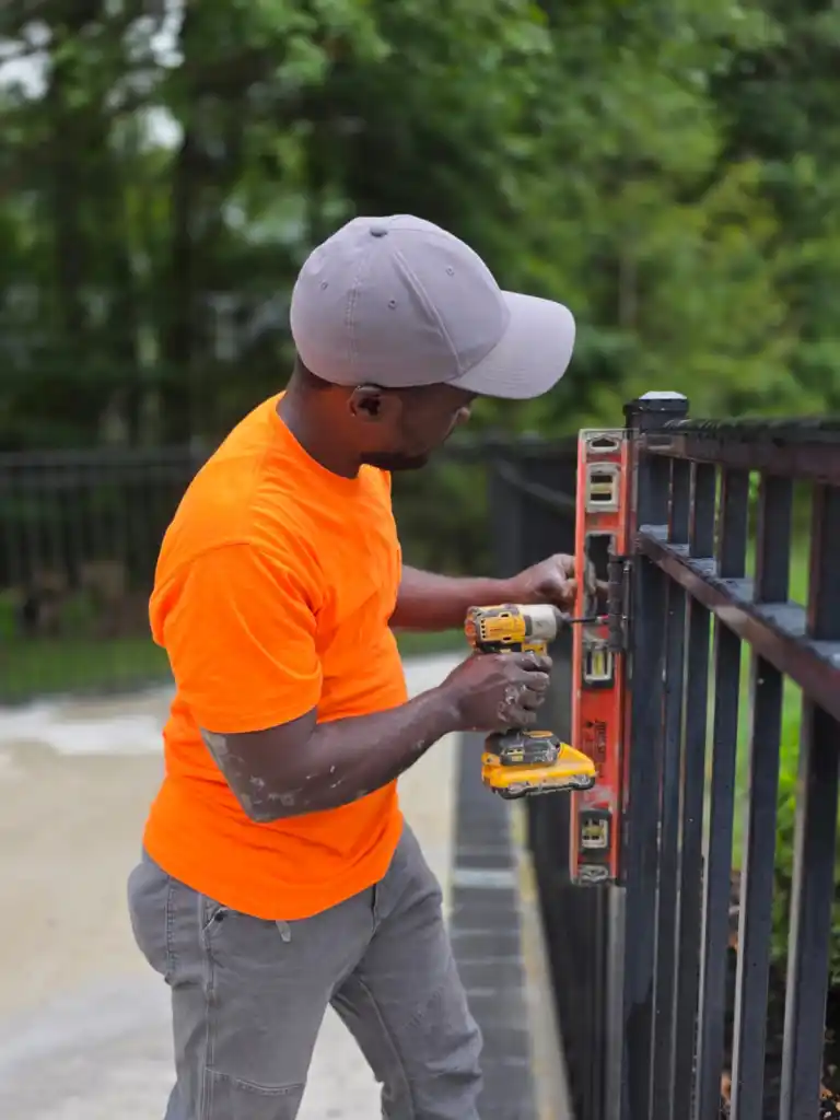 Vaillant réparent une clôture de patio arrière pour un résident de Columbus, Ohio, le mercredi 12 août 2026. Photo de Rupal R. Shah pour The Haitian Times.