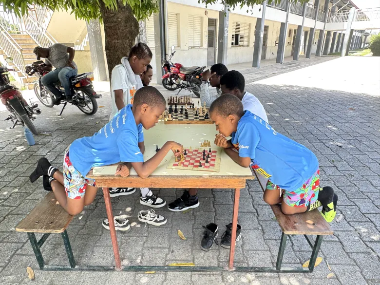 Children learn to play chess during “Let’s Play Together” on Saturday, Aug. 15, 2026, at Lycée Anacaona in Léogâne, Haiti. Photo by Daniella Saint-Louis for The Haitian Times. 
