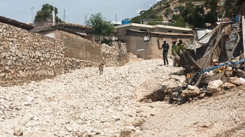 Residents assess rockfalls on Bienac Mountain in Gonaïves after heavy rains triggered flooding and landslides in several neighborhoods. Ka-Soleil, Bois-d’Homme, Praville and Gatreau were among the hardest-hit areas. Wednesday, Sept. 2, 2026. Photo by Onès Joseph for The Haitian Times. 
