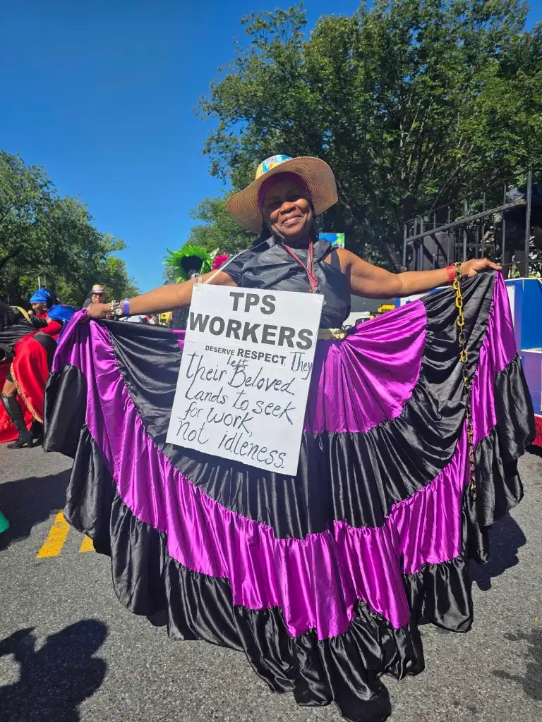 Jocelyne Gay défile avec une pancarte en soutien au projet de loi sur le TPS, S. 4814, lors de la parade du Jour des Antilles à Brooklyn, N.Y., le 7 septembre. Plusieurs élus appellent le Congrès à adopter la loi. Photo de Darlie Gervais pour The Haitian Times.