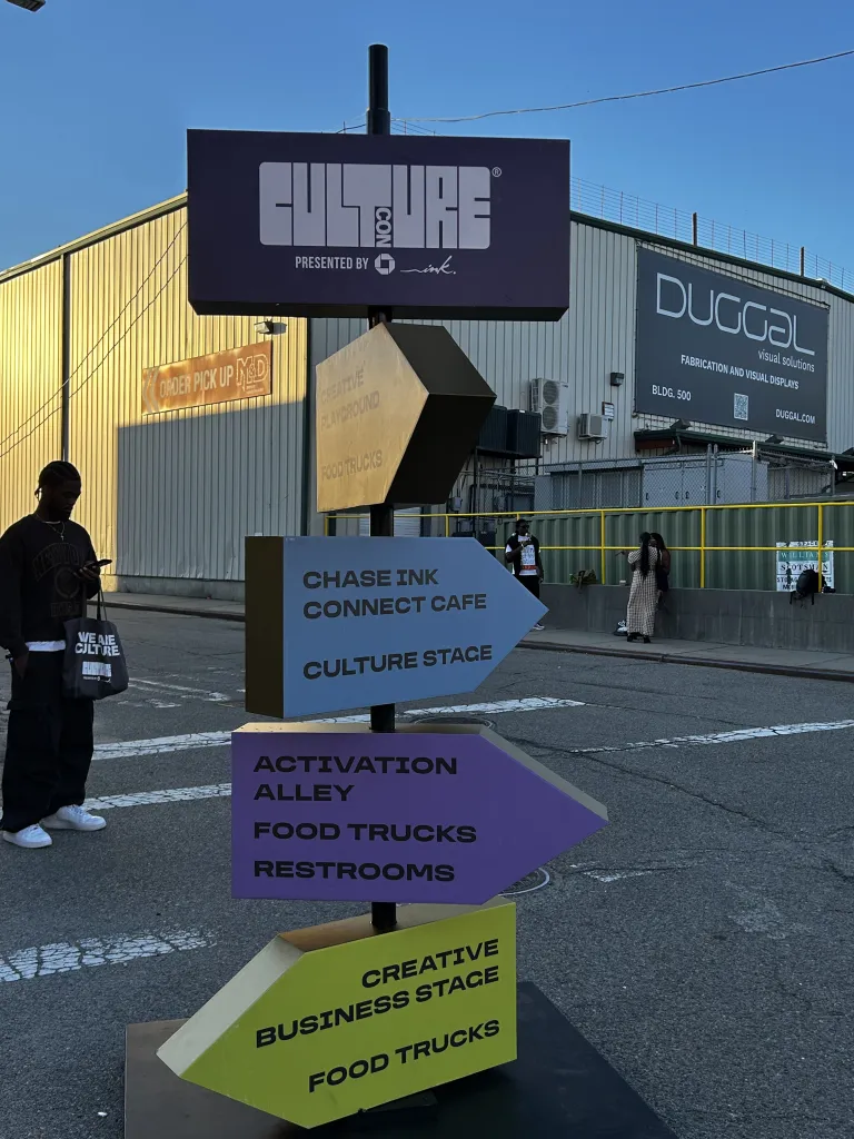 Colorful directional signs guide attendees to stages, food trucks and other attractions at CultureCon 2026 at the Brooklyn Navy Yard in Brooklyn, New York. Photo by Catherine Roth / The Haitian Times
