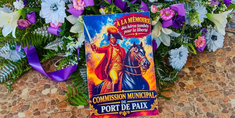 Une inscription portant ‘En mémoire des héros tombés pour la liberté’ apparaît à côté d’une gerbe déposée au mémorial lors de la commémoration du 19 octobre 2026 à Port-de-Paix. Photo par Kervenson Martial / The Haitian Times.