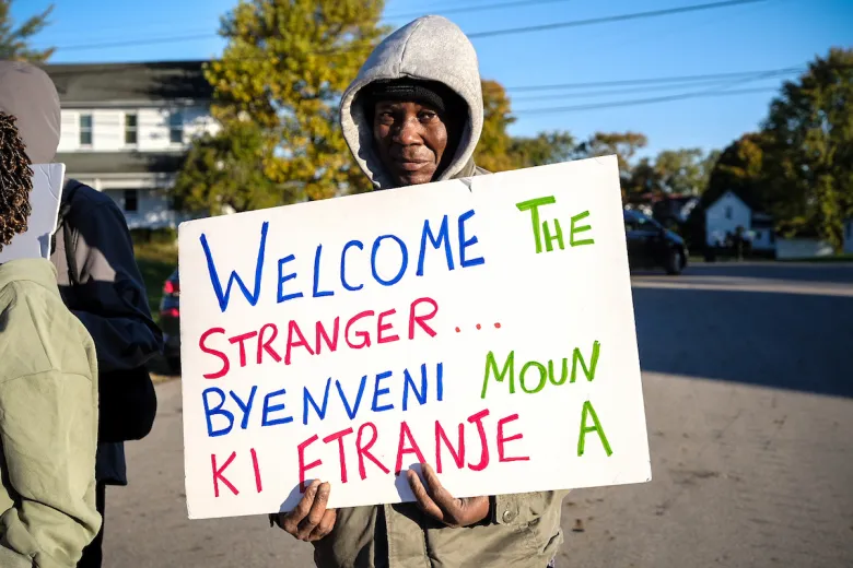 Un manifestant haïtien brandit une pancarte durant le cortège à Springfield, Ohio, le 21 octobre 2026.